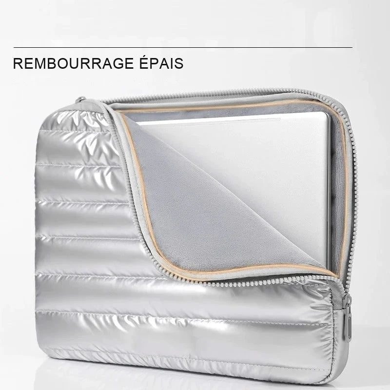 Housse matelassée argentée entrouverte, ordinateur portable glissé à l'intérieur, doublure intérieure et fermeture éclair visibles.
